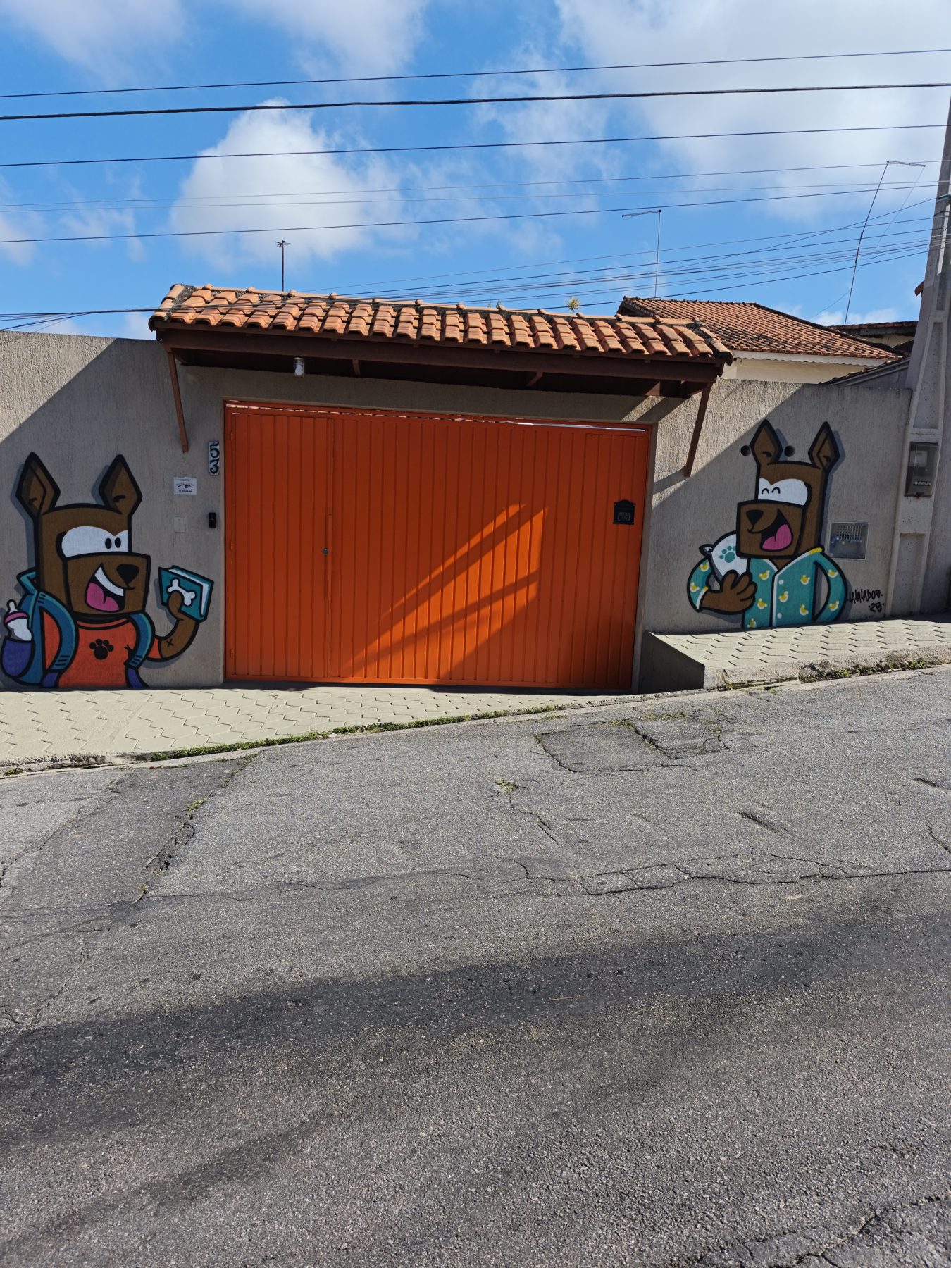 Fachada do hostel com portão laranja e grafite de cachorros